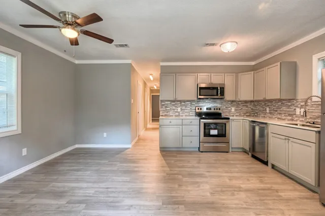 a kitchen with granite countertop a stove top oven a sink dishwasher and a refrigerator with wooden floor