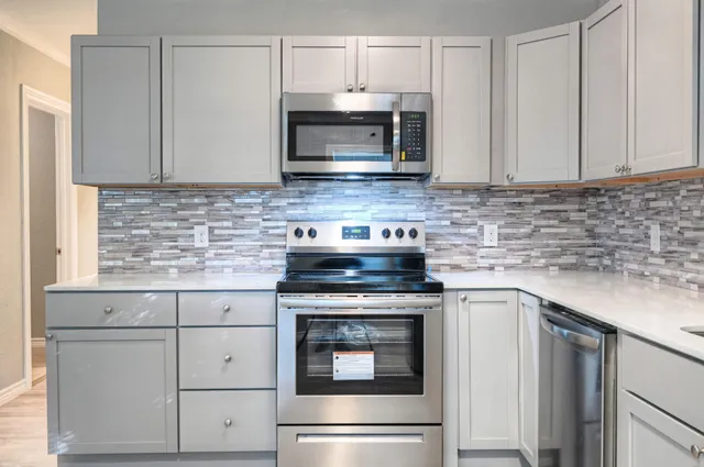 a kitchen with granite countertop white cabinets and stainless steel appliances