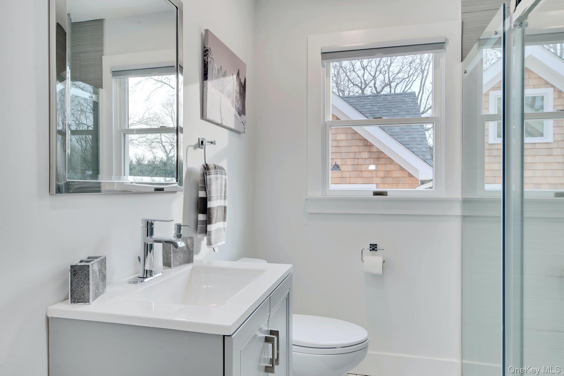550 Krause Road Mattituck, NY 11952 - Photo 22 of 34 a bathroom with a toilet a sink a vanity a window and mirror