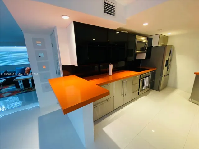 a large kitchen with stainless steel appliances a stove a refrigerator a sink and a microwave