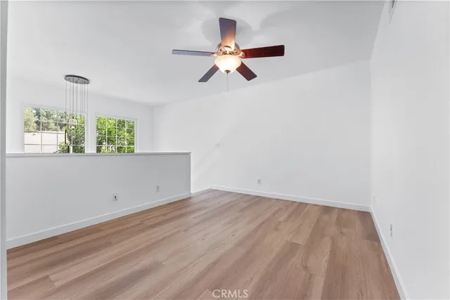 an empty room with windows and fan