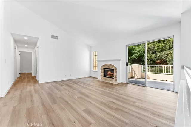 a view of empty room with wooden floor and fireplace
