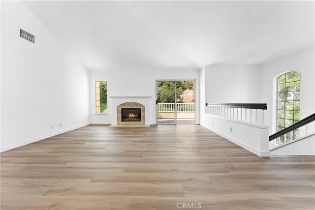 a view of empty room with wooden floor and fireplace