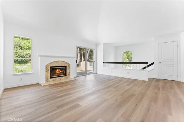an empty room with windows and fireplace