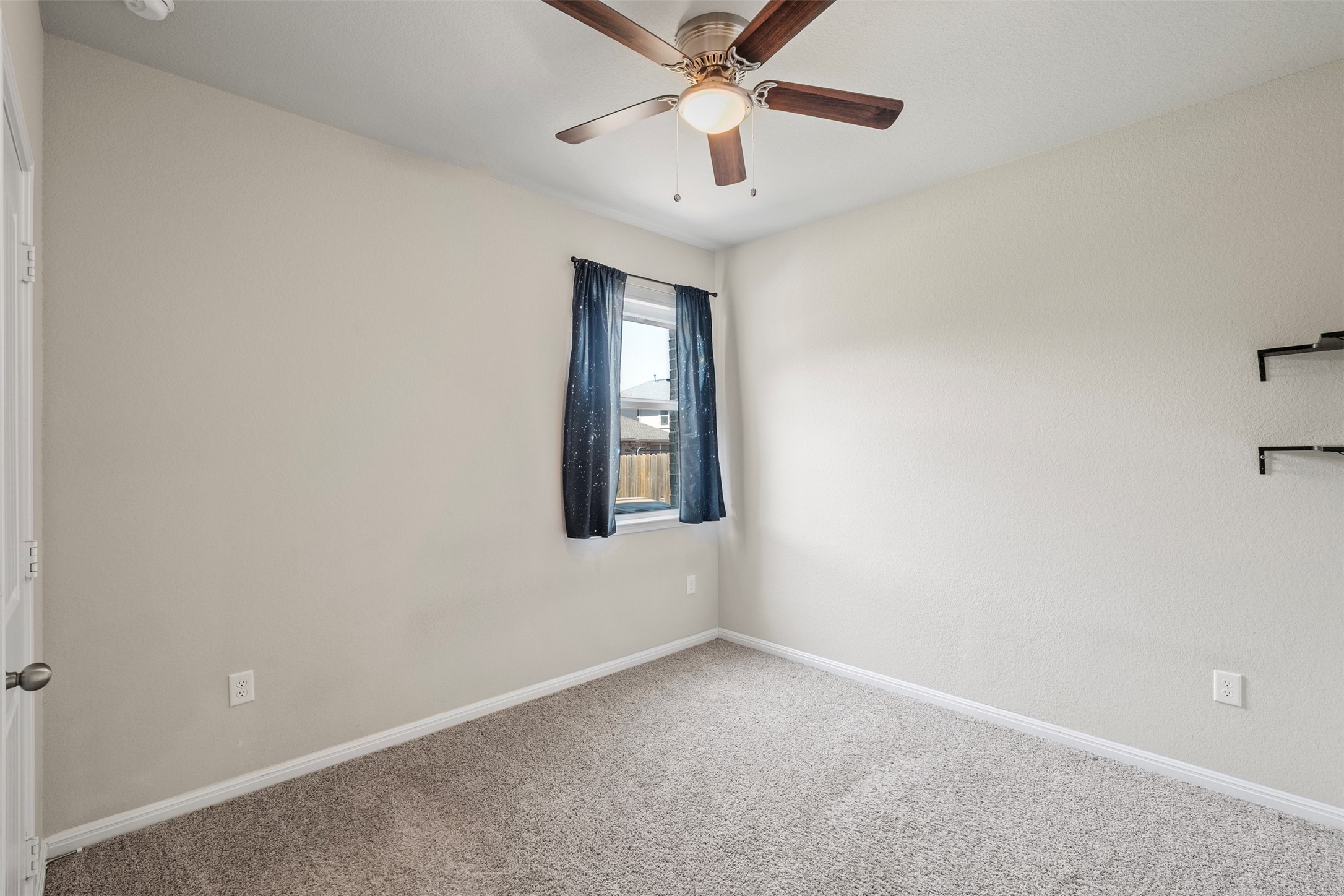 120 Ellinger Road Georgetown, TX 78626 - Photo 18 of 28 Carpeted room featuring a ceiling fan with integrated lighting, a window with dark curtains, and wall-mounted shelving