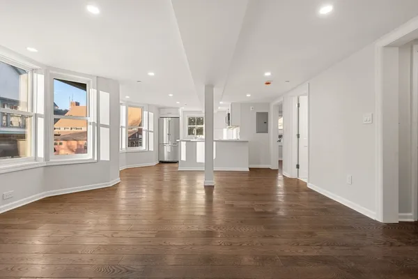 a view of an empty room with a window and wooden floor