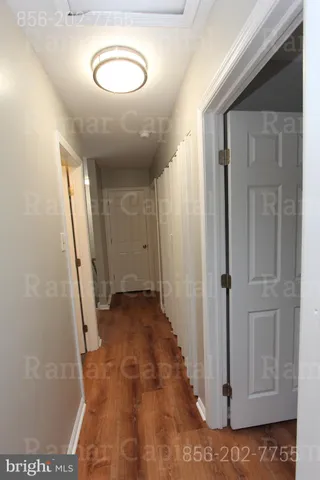 an empty room with wooden floor chandelier fan and windows