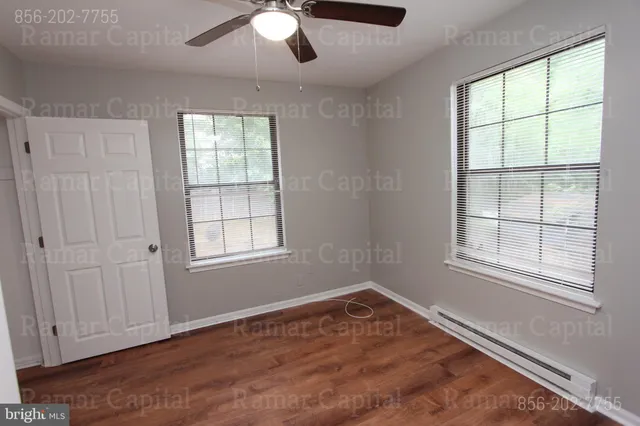 an empty room with windows and fan