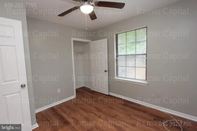 an empty room with a window and chandelier fan