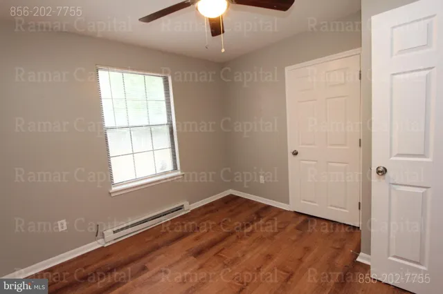 an empty room with wooden floor ceiling fan and windows