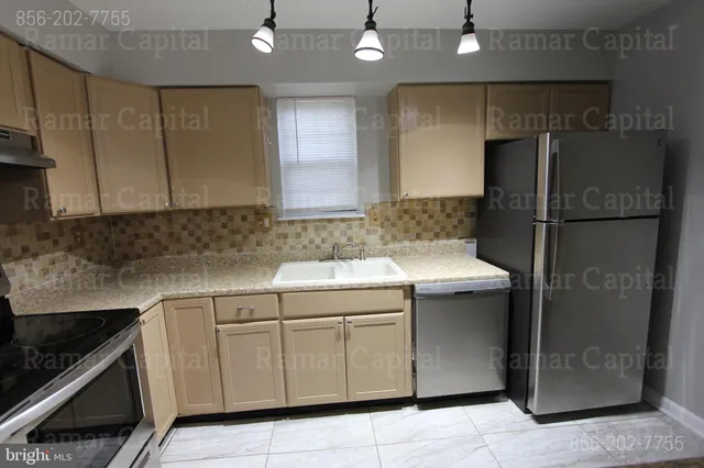 a kitchen with a sink dishwasher a refrigerator and cabinets