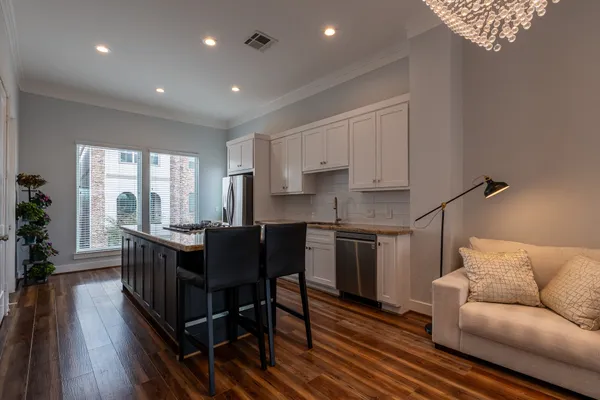 a view of kitchen with kitchen island stainless steel appliances wooden floor dining table and chairs