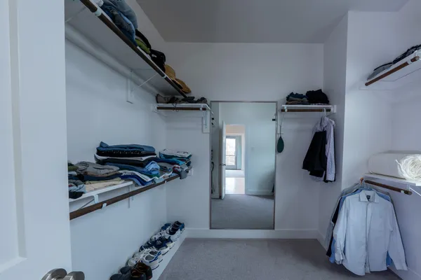 a view of walk in closet with clothes and shoes