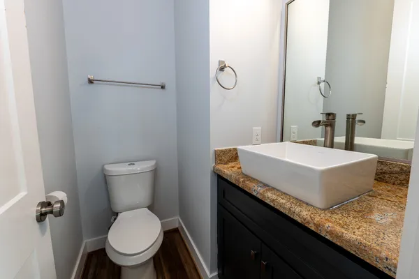 a bathroom with a granite countertop sink a toilet and a mirror