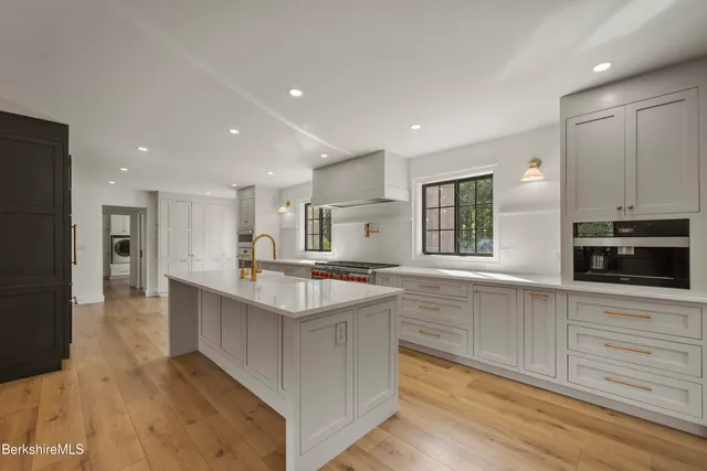 a view of a kitchen with kitchen island a large counter top space a sink stainless steel appliances and cabinets