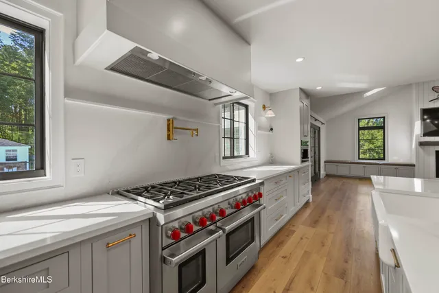 an empty room with wooden floor a ceiling fan and windows