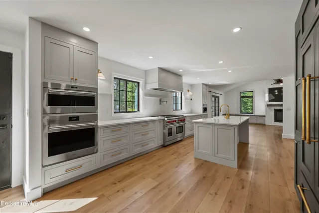 an empty room with windows fireplace and wooden floor