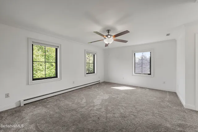 an empty room with windows and fan