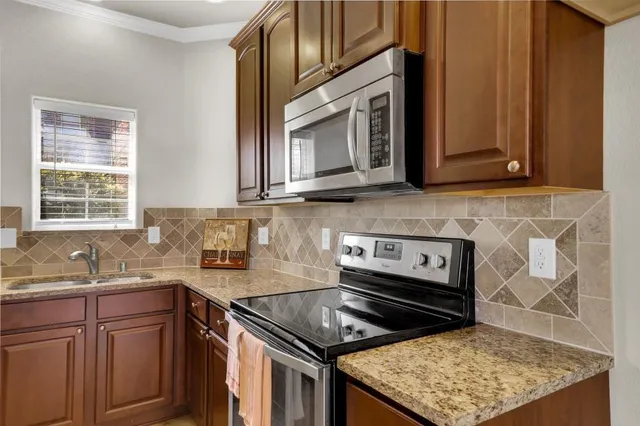 a kitchen with stainless steel appliances granite countertop a stove a sink and a microwave