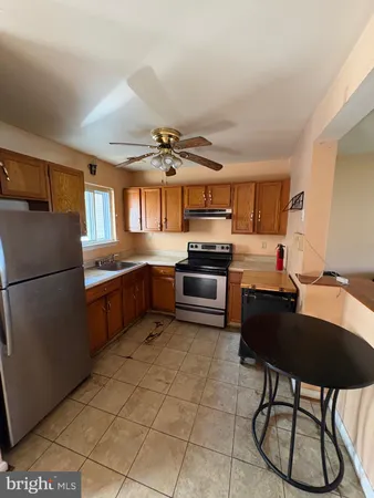 a living room with couches and kitchen view with wooden floor