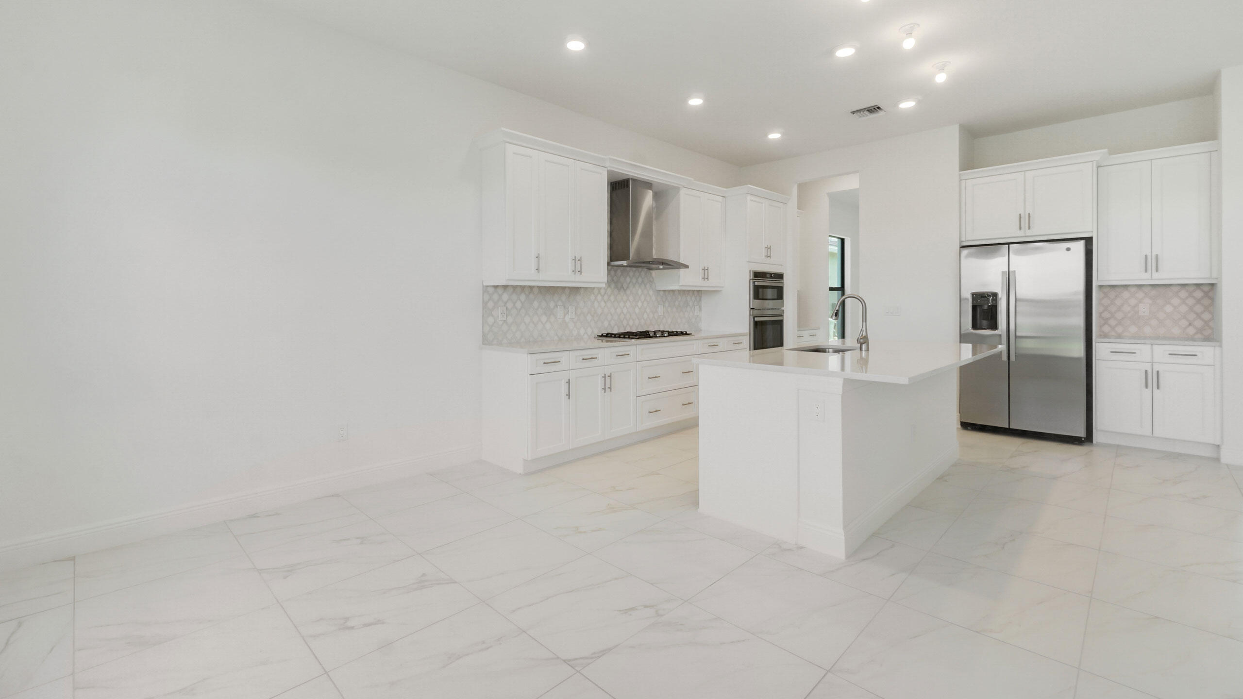 15739 Cresswind Place Westlake, FL 33470 - Photo 9 of 48 a large white kitchen with a sink stainless steel appliances and cabinets
