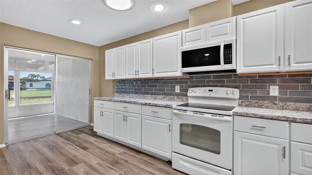 7280 Scotland Circle Weeki Wachee, FL 34613 - Photo 12 of 42 a kitchen with stainless steel appliances granite countertop a stove microwave and sink