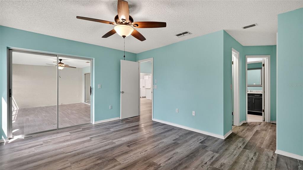 7280 Scotland Circle Weeki Wachee, FL 34613 - Photo 22 of 42 a view of an empty room with wooden floor and a ceiling fan