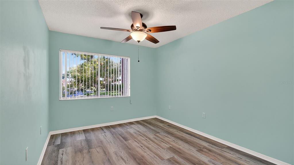 7280 Scotland Circle Weeki Wachee, FL 34613 - Photo 28 of 42 an empty room with wooden floor chandelier fan and windows
