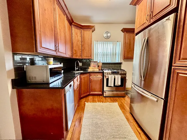 a kitchen with stainless steel appliances granite countertop a granite counter tops and a view of living room