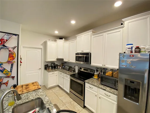 a kitchen with stainless steel appliances granite countertop a table chairs and a sink