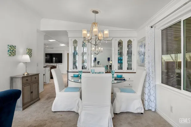 a dining room with furniture a chandelier and kitchen view