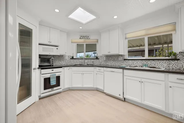 a kitchen with granite countertop white cabinets and stainless steel appliances