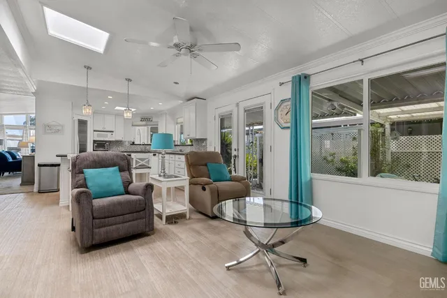 a living room with furniture kitchen view and a large window