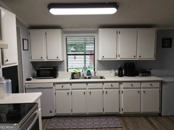 a kitchen with stainless steel appliances granite countertop a stove a sink and white cabinets