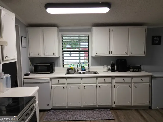 a kitchen with stainless steel appliances granite countertop a stove a sink and white cabinets