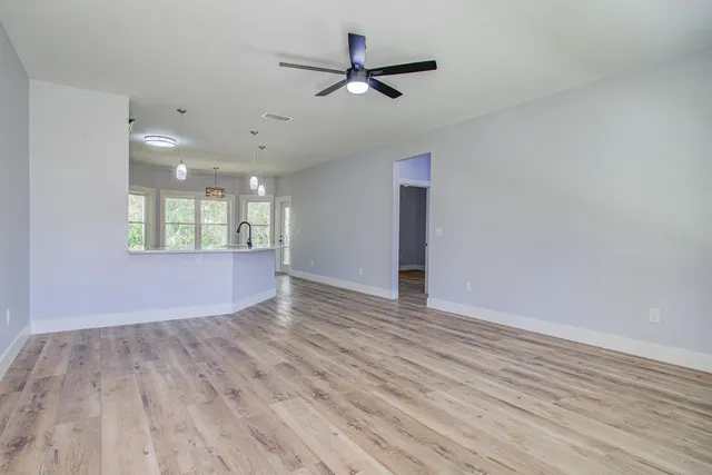 a view of an empty room with a window and wooden floor