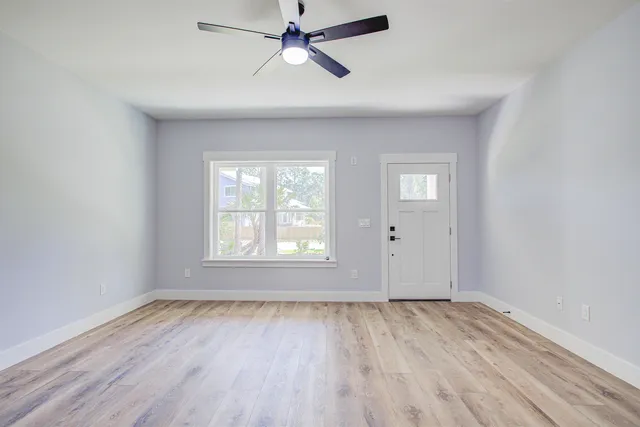 a view of an empty room with a window and wooden floor