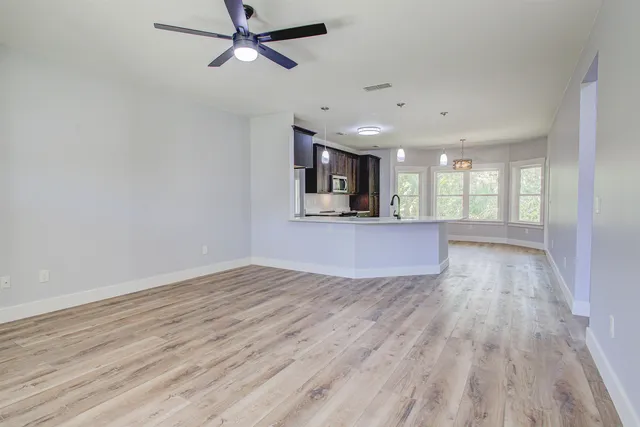 a living room with furniture kitchen view and a wooden floor