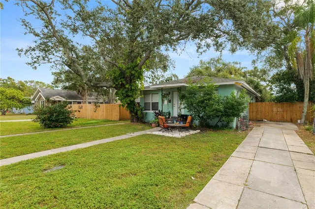 a view of a patio with table and chairs under an umbrella with large trees
