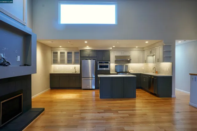 a large kitchen with stainless steel appliances granite countertop a large counter top and a fireplace