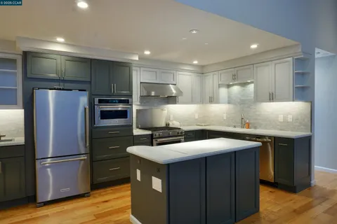 a kitchen with kitchen island a counter top space cabinets stainless steel appliances and wooden floor