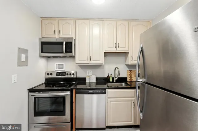 a kitchen with stainless steel appliances granite countertop white cabinets a stove a microwave and a refrigerator