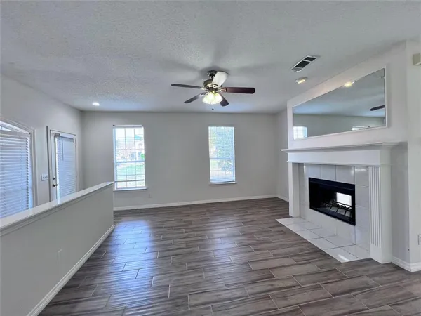 a view of an empty room with wooden floor fireplace and a window