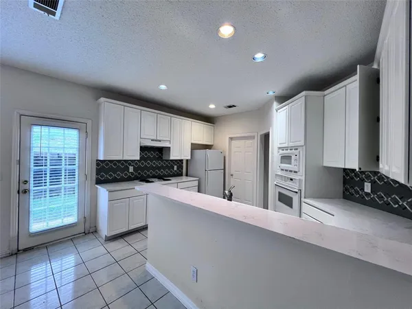 a large kitchen with stainless steel appliances kitchen island granite countertop a refrigerator and a stove top oven
