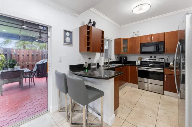 a kitchen with stainless steel appliances granite countertop a stove top oven a sink a dining table and chairs