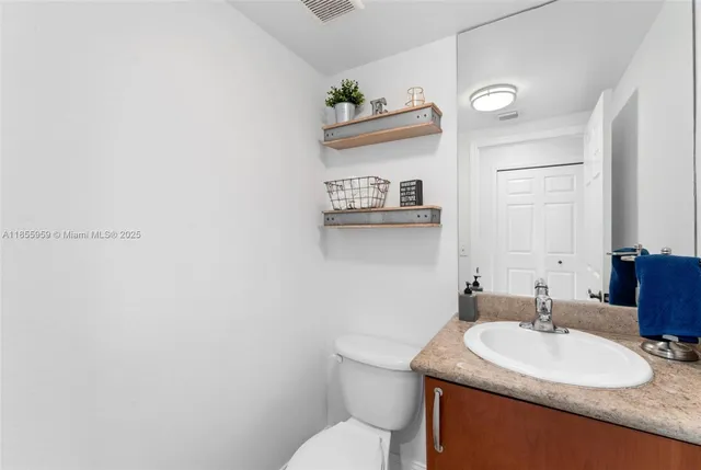a bathroom with a granite countertop sink a toilet and a mirror