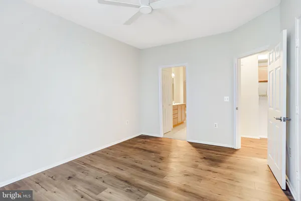an empty room with chandelier fan and windows