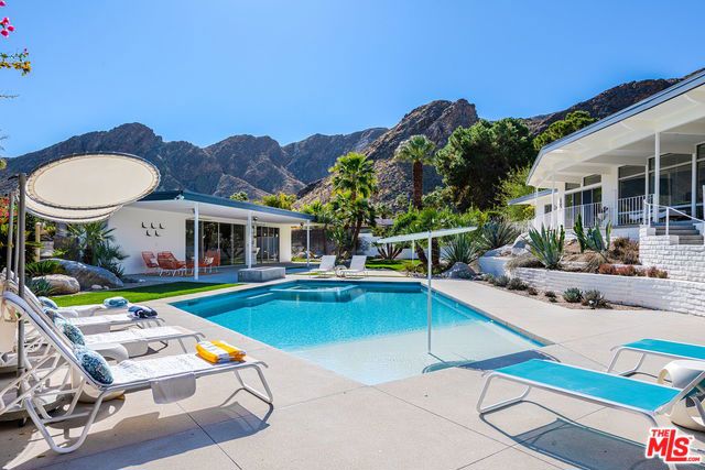 a view of a house with pool and chairs
