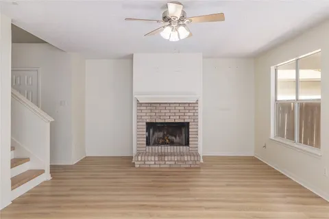 a view of an empty room with wooden floor fireplace and a window