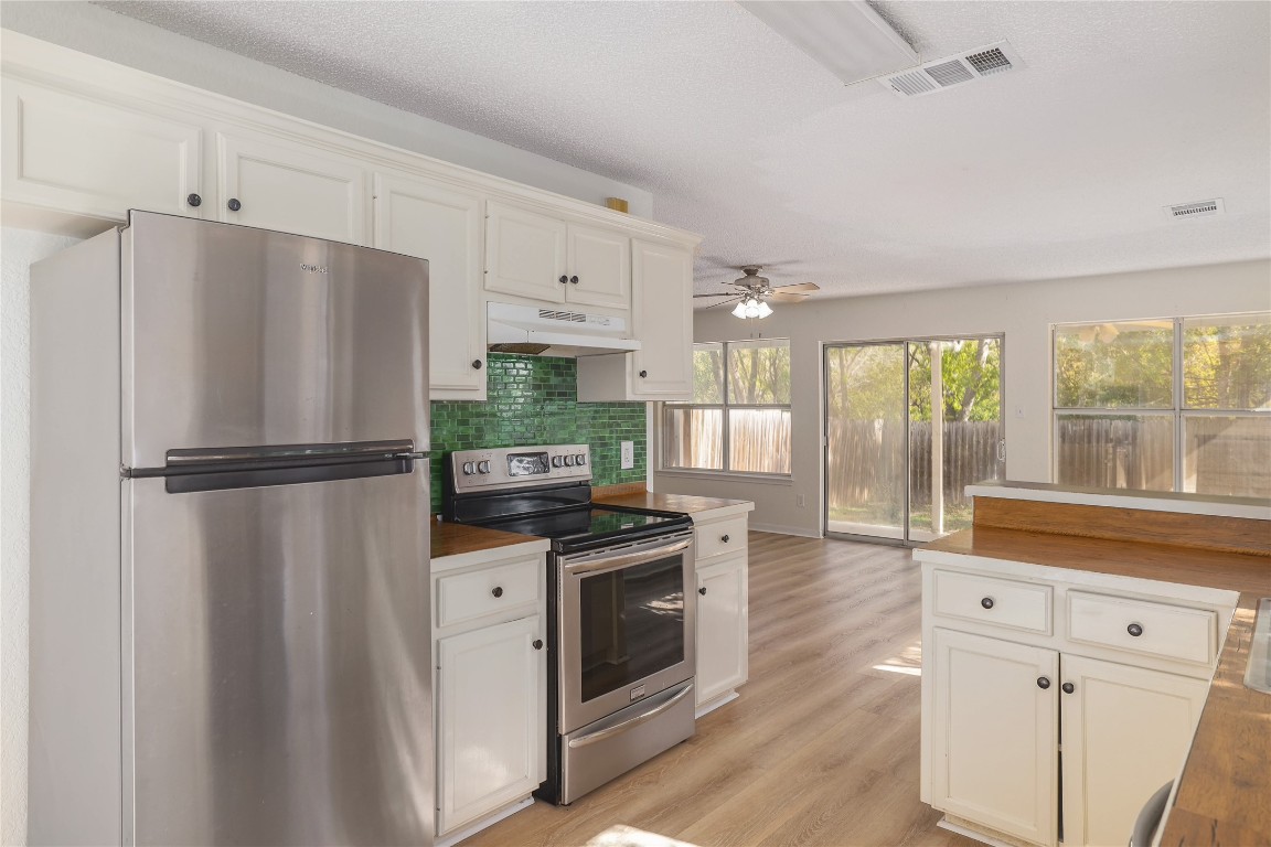 2229 Jasmine Path Round Rock, TX 78664 - Photo 5 of 28 a kitchen with granite countertop a refrigerator a sink a stove and white cabinets